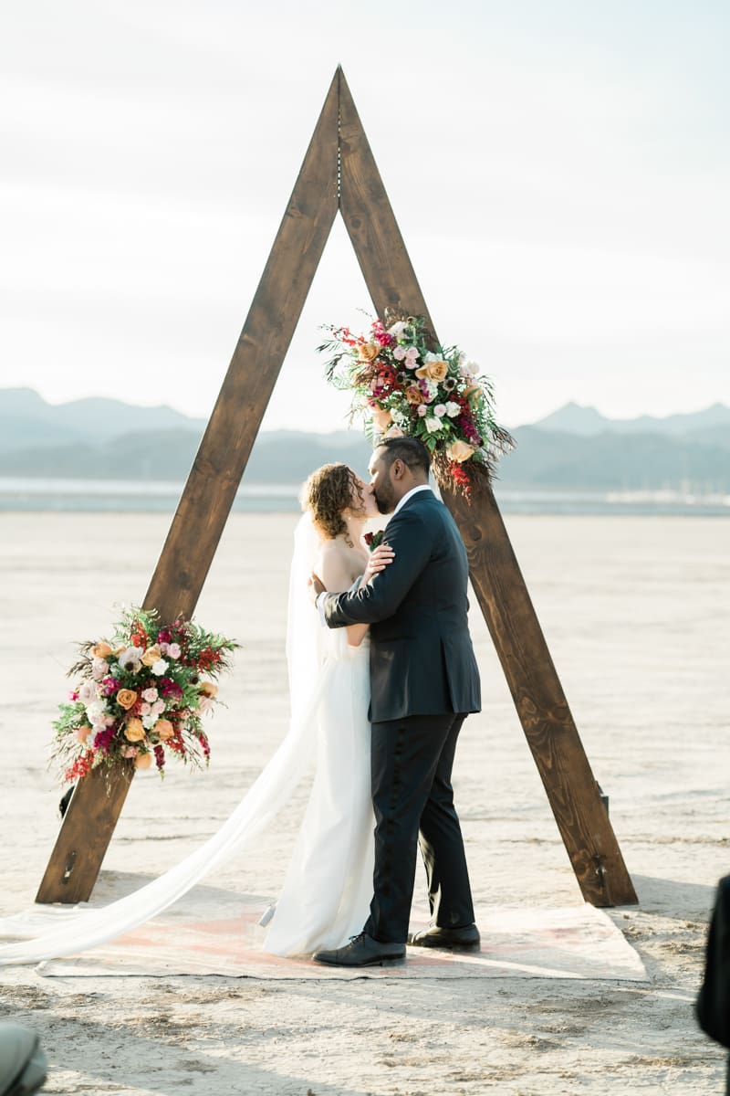 Newlyweds kissing under arch in the Dry Lake Bed in Boulder City, NV.