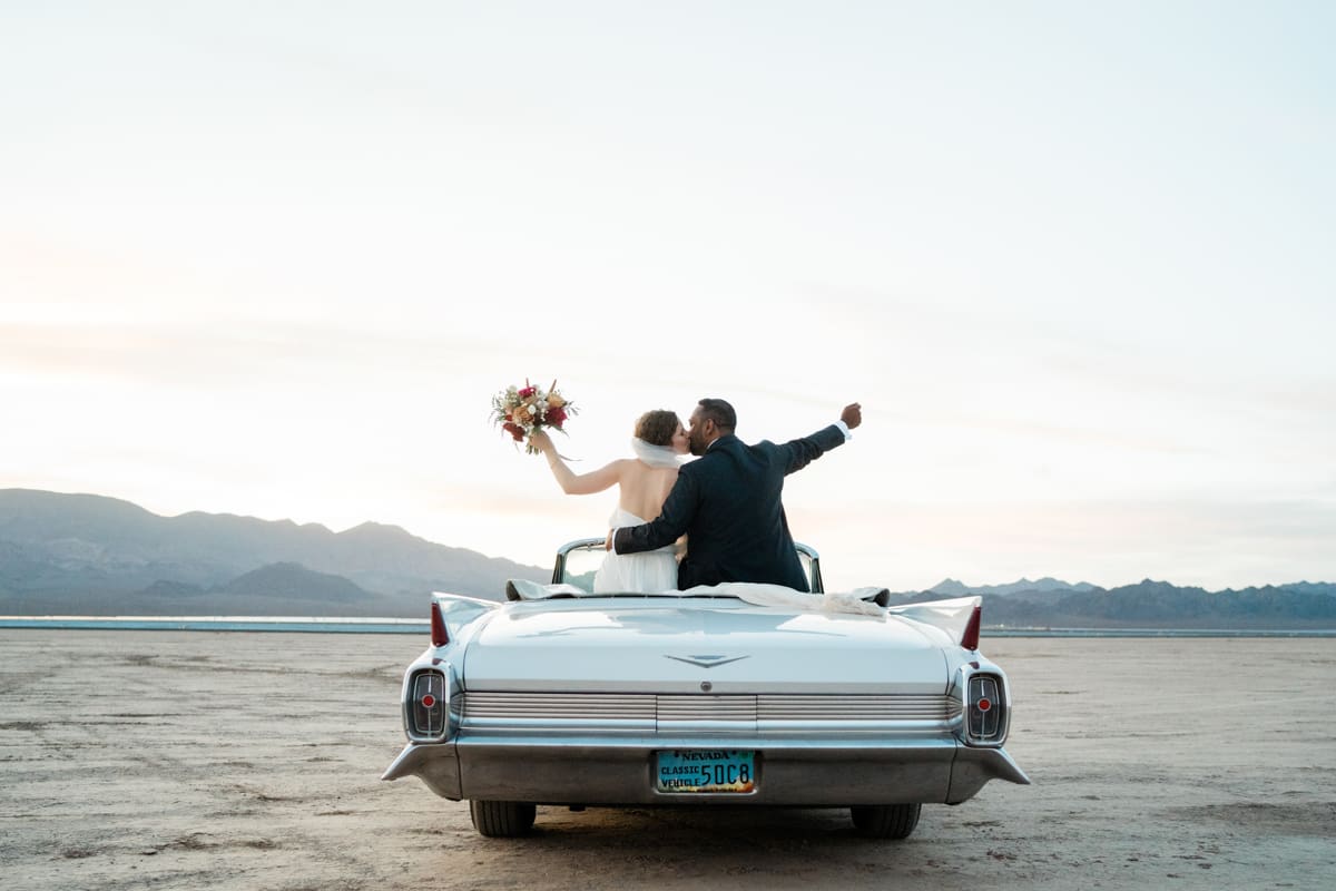 Newlyweds kissing in a classic car in the Dry Lake Bed in Boulder City, NV.