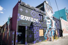 A black building with purple tribal markings and the word \"aware\" in white with red and blue accents along with a black, white, red, and blue image of a Native American wearing a feather headdress.