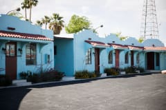 A photo of the buildings that make up Lucky Motel, teal brick buildings with adobe style tile roof.