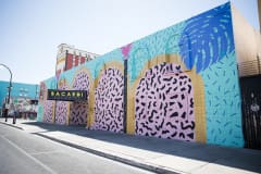 A photo of the Bacardi Art Motel, which is painted in bright colors and an early '90s art style and includes blue palm leaves.