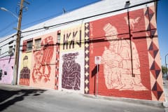 A mural depicting the back of a man\'s head and the words \"Remember\" also features various animals and a man holding a dog with a rooster above him. The predominant colors are red, black, light yellow, and white.