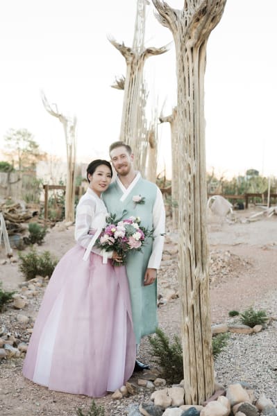 A bride and groom pose amongst Saguaro Cacti skeletons at Cactus Joe’s Blue Diamond Nursery.