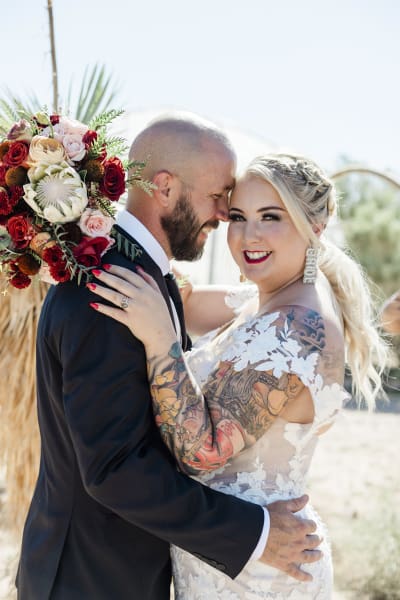 A groom and bride embrace on their wedding day at Cactus Joe’s Blue Diamond Nursery.