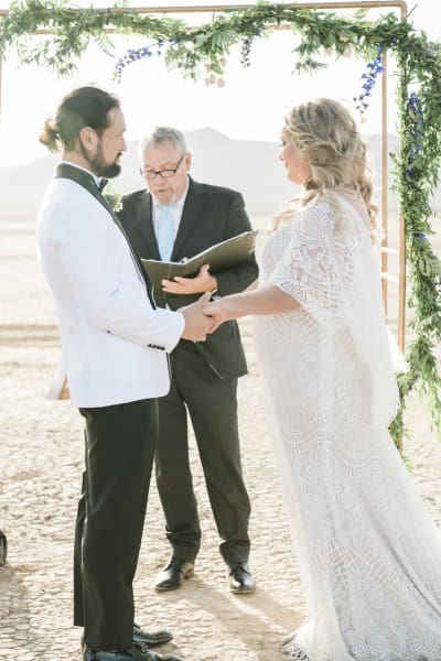 A wedding officiant reads from his prepared remarks as he marries a couple on the Dry Lake Bed in Boulder City, Nevada, outside Las Vegas. The couple holds hands while listening to officiant.