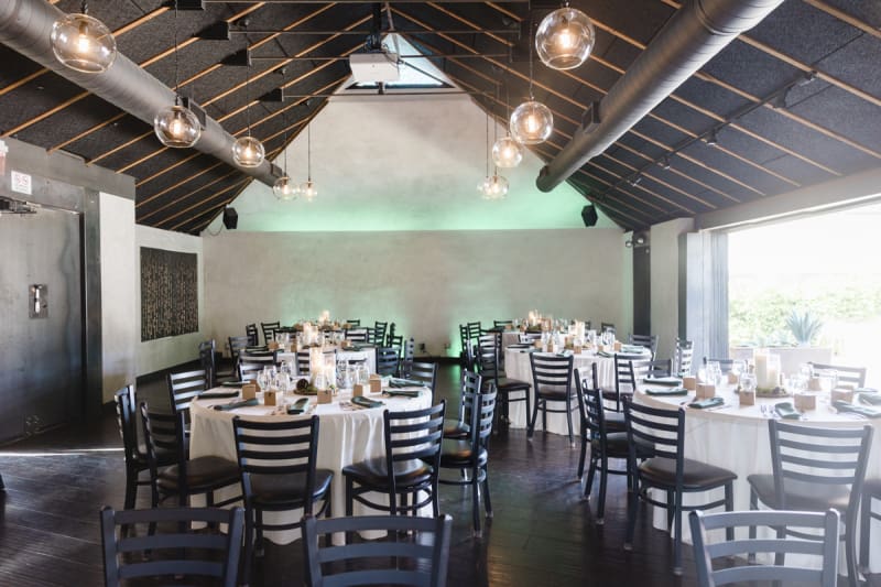 The main room at Forge Social House is set up with tables and chairs for a wedding reception.