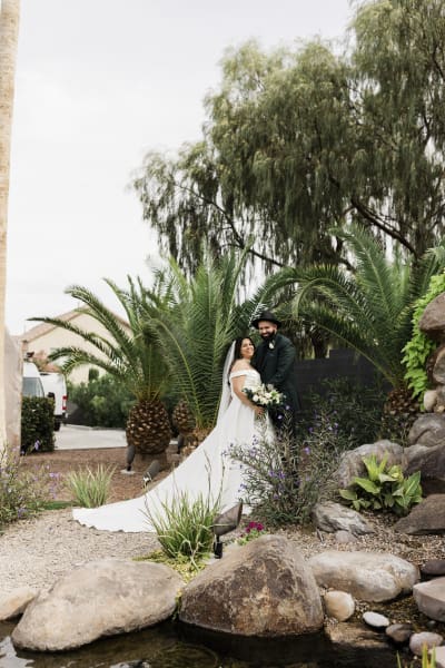 A bride and groom stand together above a water garden feature as they pose for wedding portraits.