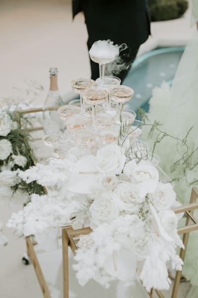 A display of white roses is set amongst a Champagne tower.