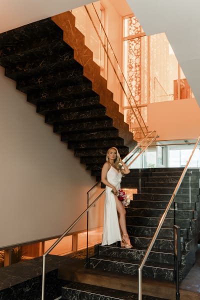A bride poses on a photogenic black and gold staircase located inside the Beverly Theater.