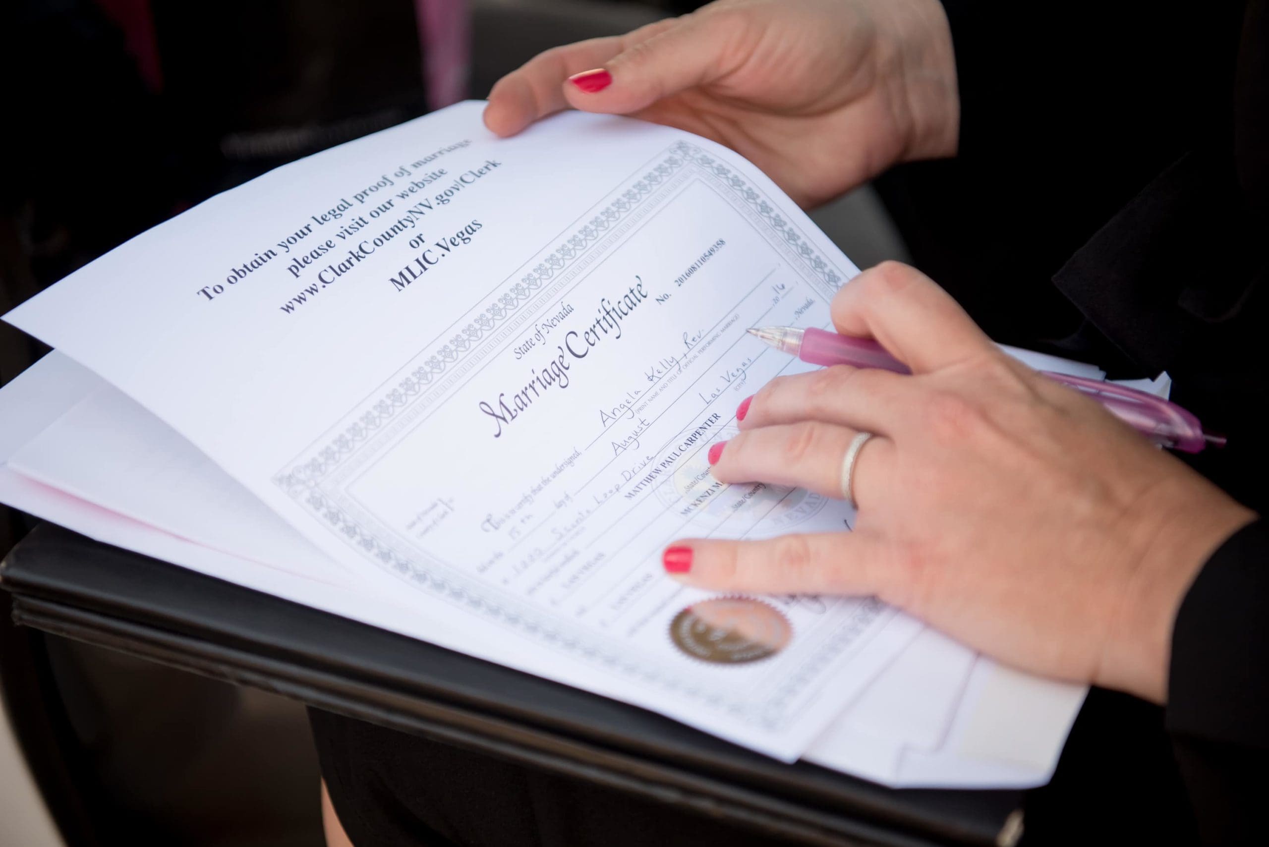 Modern minister signing a marriage license for a newly married couple.