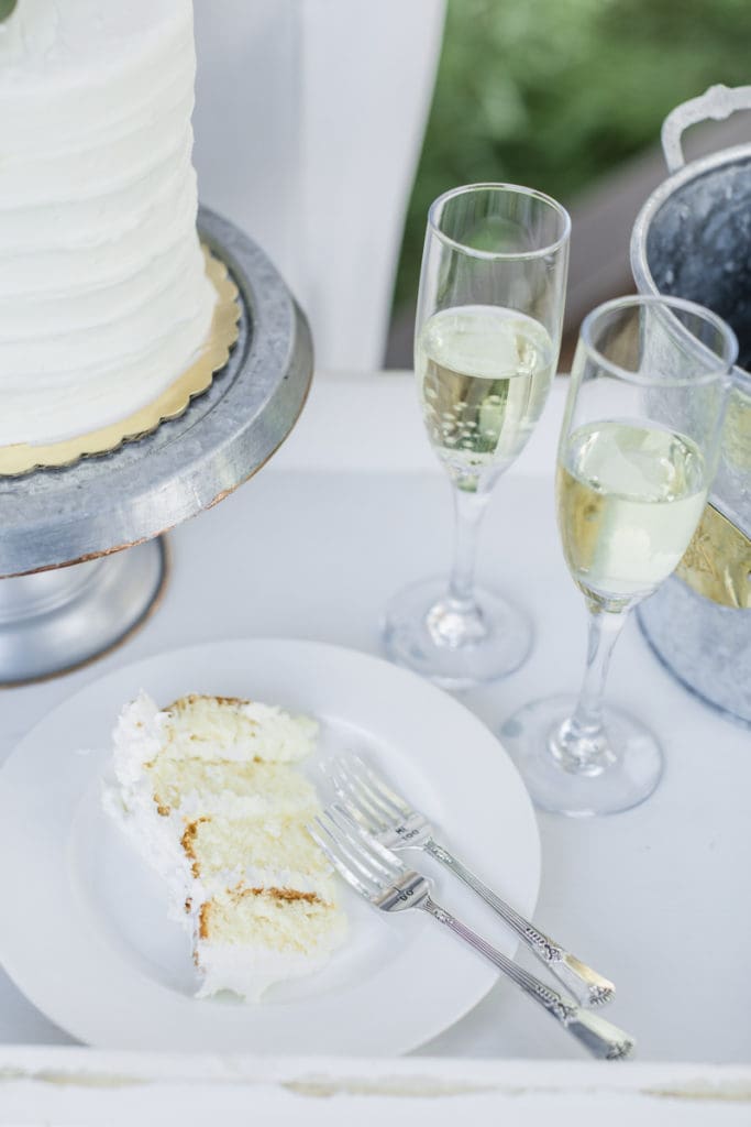 White wedding cake next to champagne glasses. 